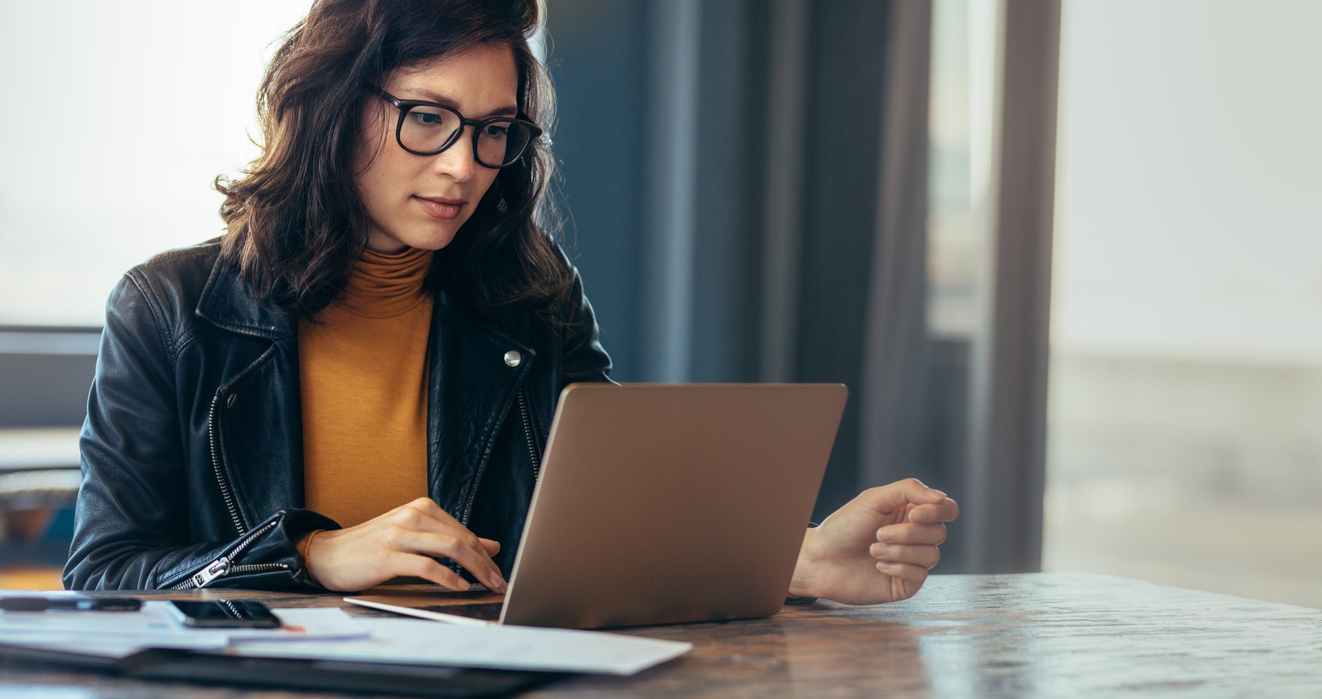 A woman sits at a desk searching for DFY marketing for her small business.